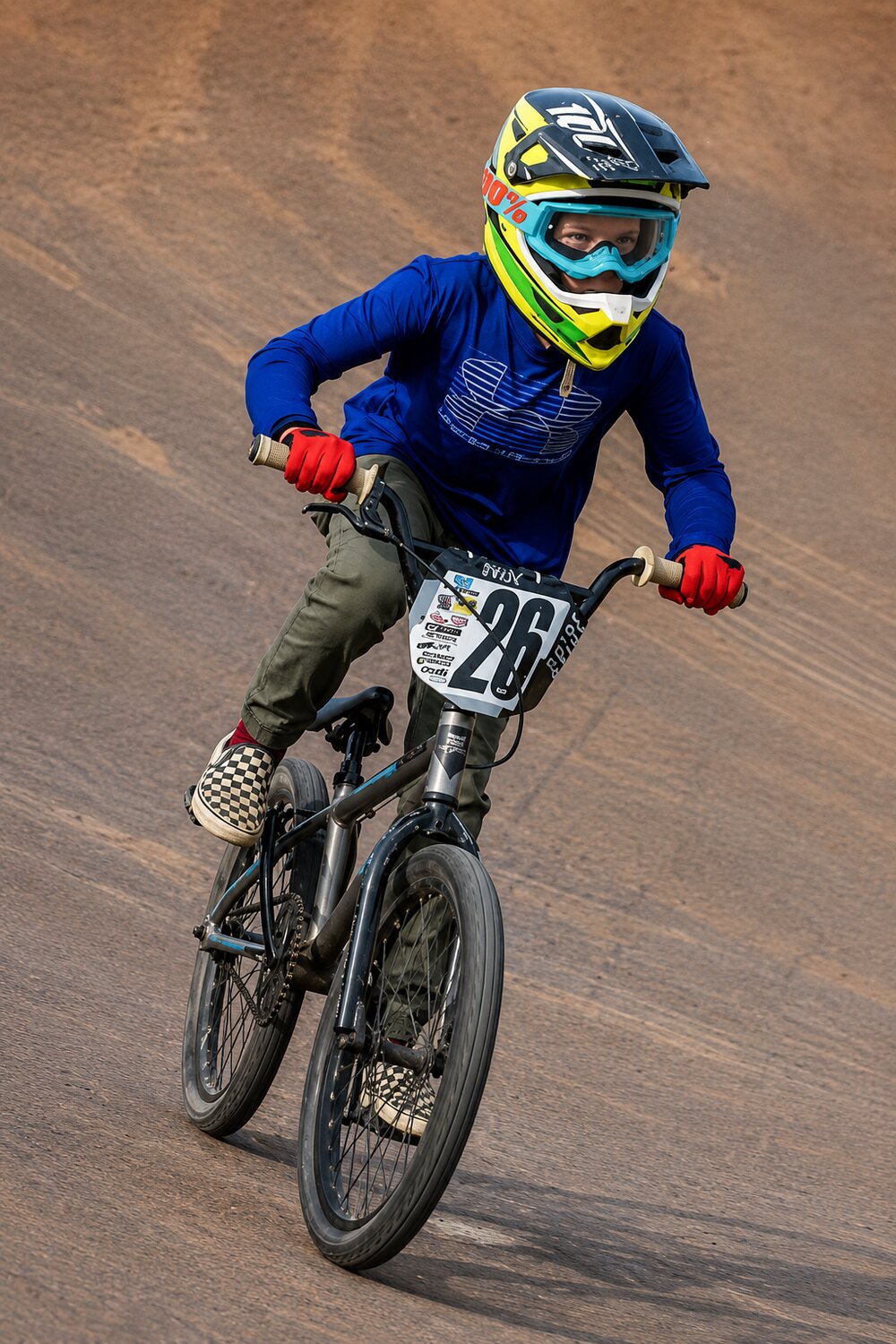 A young rider in full gear racing on the dirt track at San Diego BMX